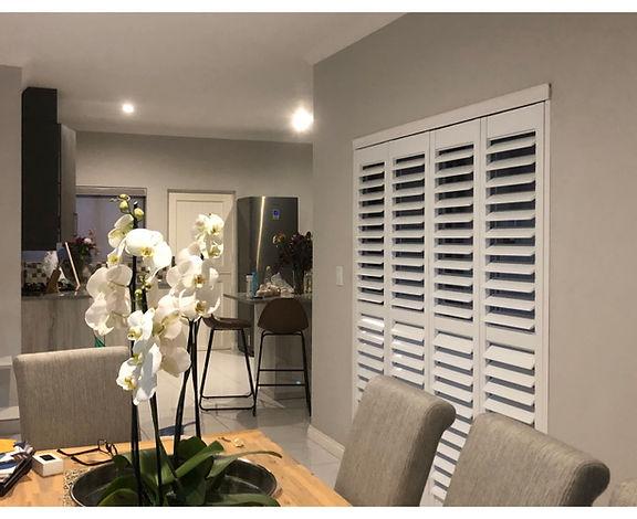 Open-plan kitchen and dining area with white shutters and an orchid, Kyalami