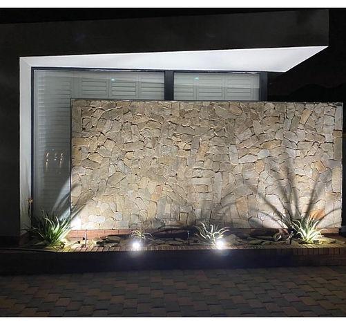 Shutters above a floodlit stacked-stone feature wall at night, Meyersdal