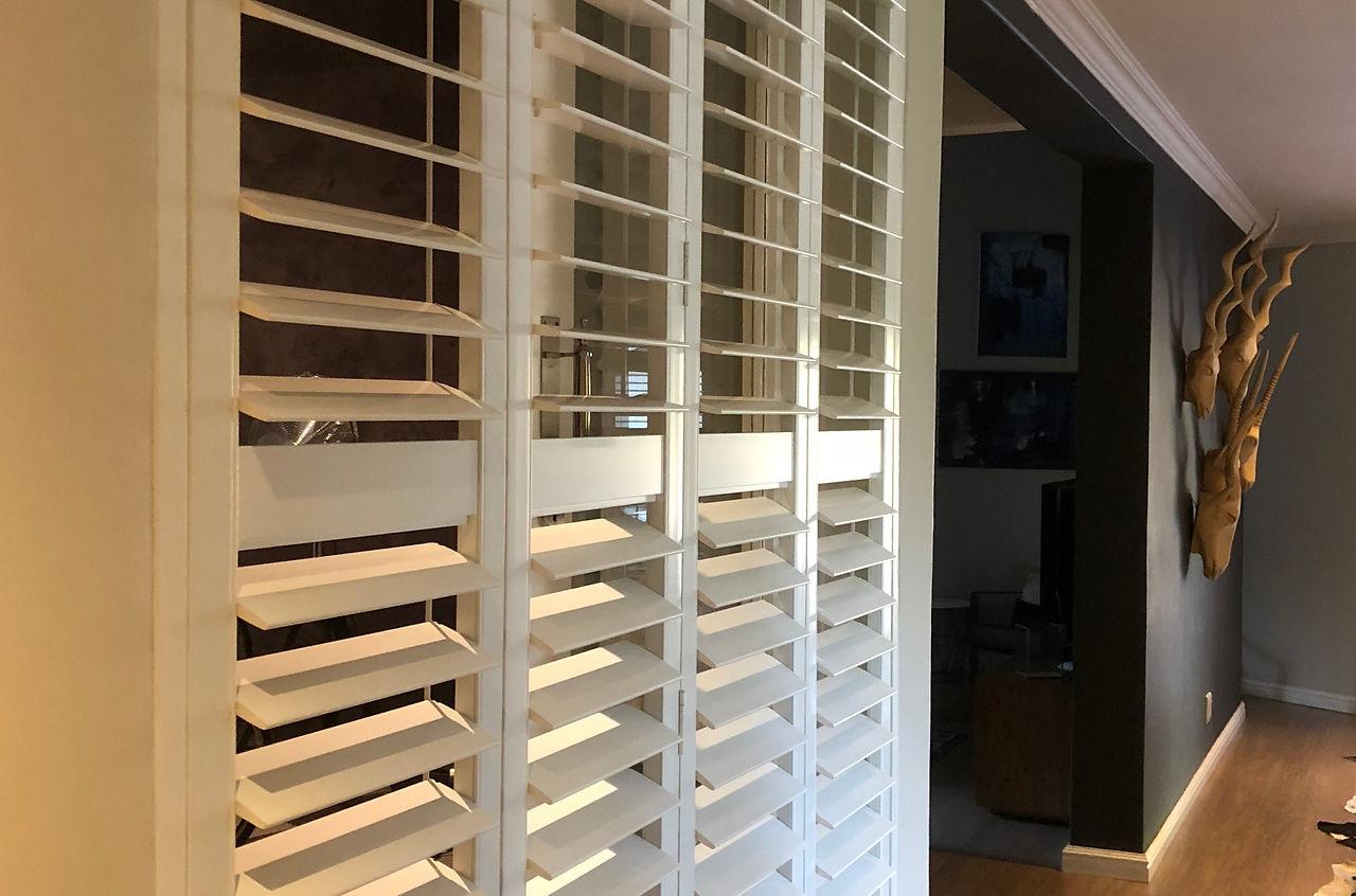 Warm daylight filtering through angled white shutter louvres