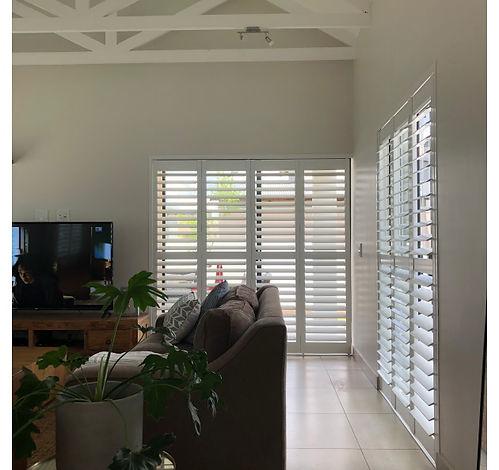 Sliding shutters across patio doors in a bright living room, Midstream