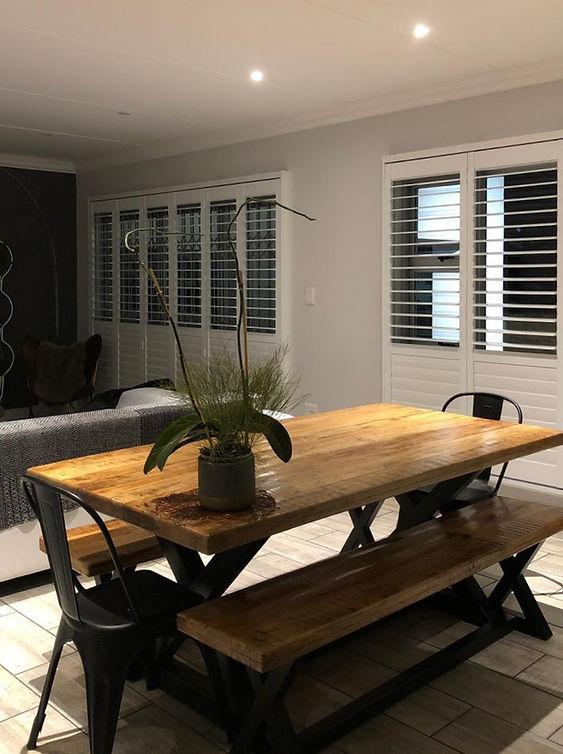 Reclaimed-wood dining room with white Rigidcore shutters framing the windows
