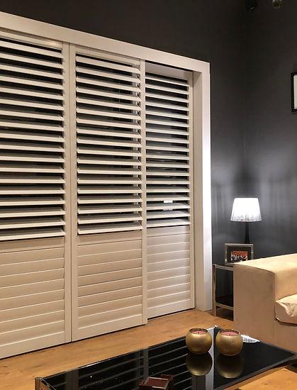 Cream Rigidcore shutters against a dark feature wall in a softly lit bedroom