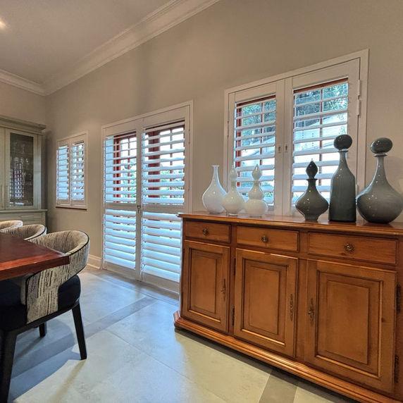 Rigidcore Thermo shutters in an elegant dining room, with soft daylight through the louvres