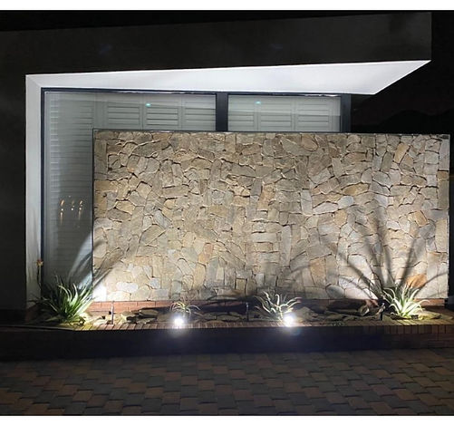 Shutters above a floodlit stacked-stone feature wall at night, Meyersdal