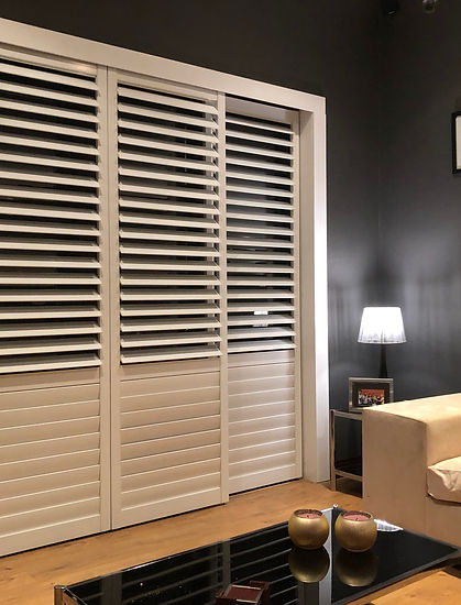 Cream Rigidcore shutters against a dark feature wall in a softly lit bedroom