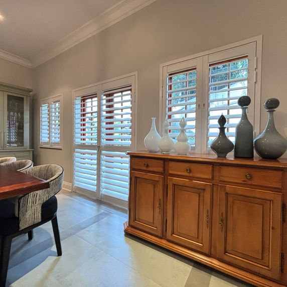 Rigidcore Thermo shutters in an elegant dining room, with soft daylight through the louvres
